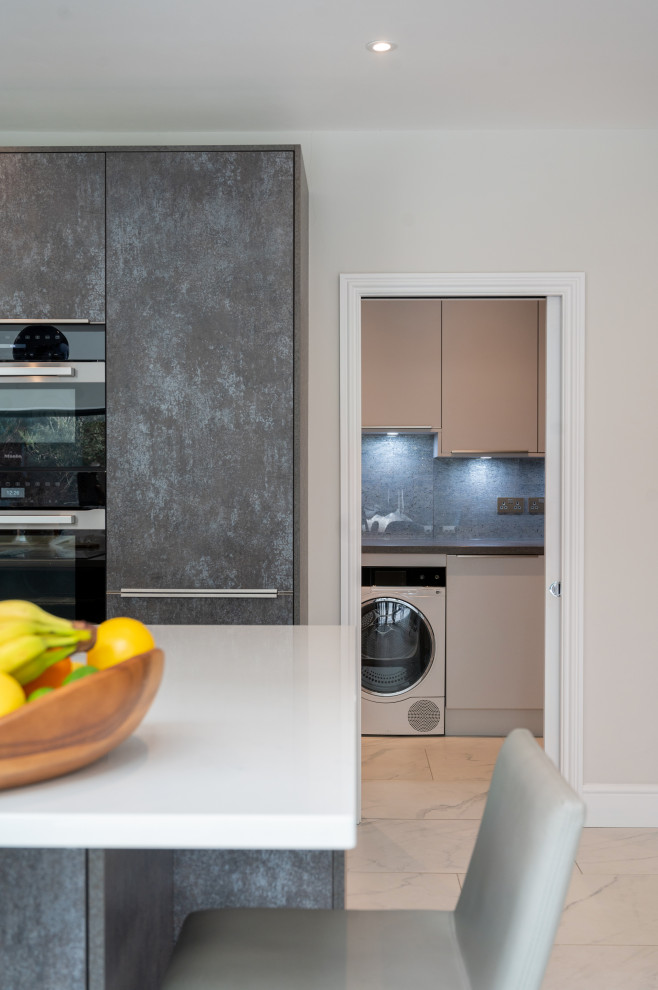 Design ideas for a large modern l-shaped open plan kitchen in Surrey with an integrated sink, flat-panel cabinets, grey cabinets, quartz worktops, blue splashback, glass sheet splashback, integrated appliances, porcelain flooring, an island, white floors, white worktops and a chimney breast.
