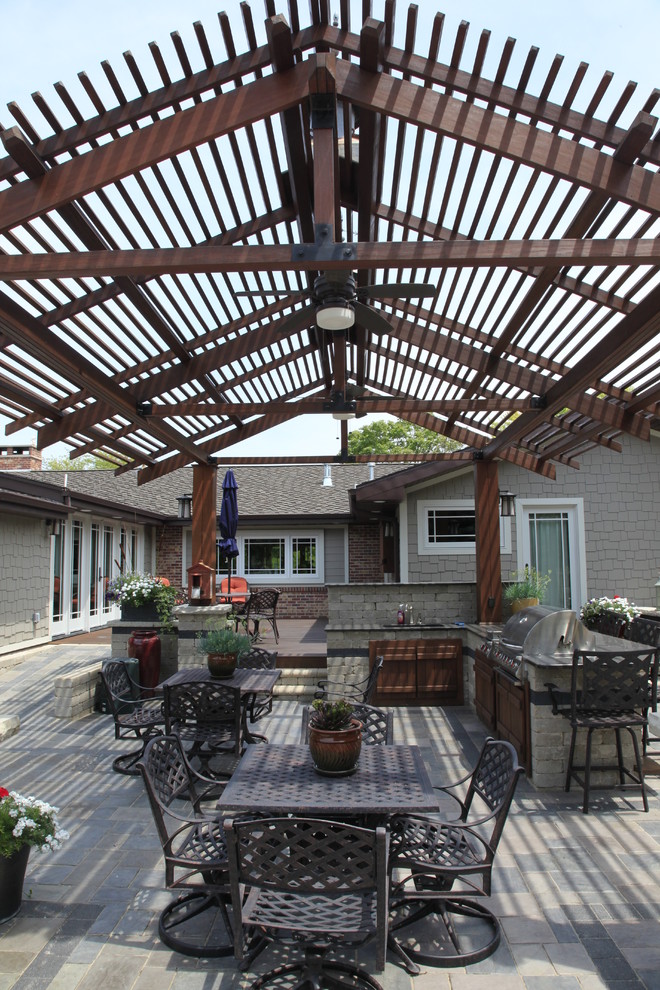 Photo of a large arts and crafts backyard patio in Other with an outdoor kitchen, concrete pavers and a pergola.