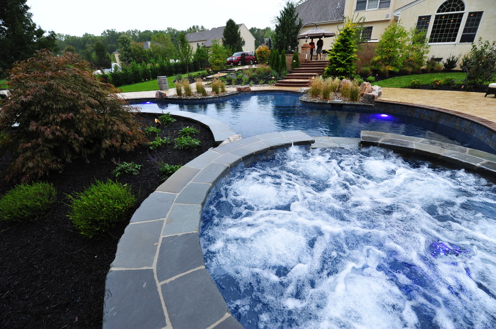 Inspiration for an expansive traditional backyard custom-shaped lap pool in New York with a hot tub and tile.