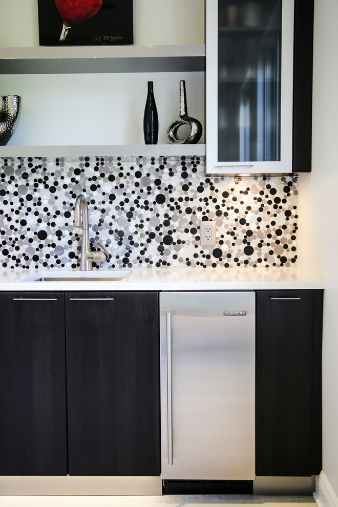 Photo of a small modern single-wall wet bar in Miami with a drop-in sink, flat-panel cabinets, dark wood cabinets, laminate benchtops, multi-coloured splashback, mosaic tile splashback, white floor and white benchtop.