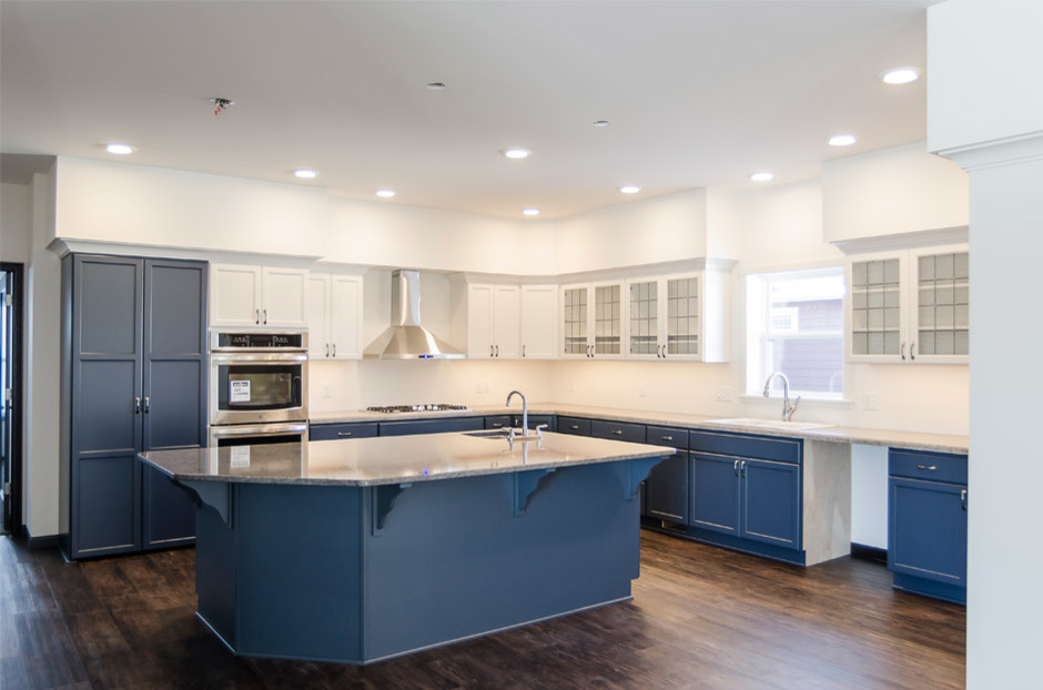 Mid-sized transitional l-shaped medium tone wood floor eat-in kitchen photo with a drop-in sink, recessed-panel cabinets, white cabinets, granite countertops, stainless steel appliances and an island