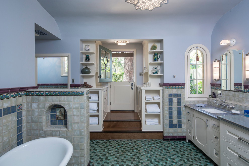 This is an example of a beach style master bathroom in Los Angeles with recessed-panel cabinets, white cabinets, a freestanding tub, a two-piece toilet, blue tile, ceramic tile, blue walls, mosaic tile floors, an undermount sink and zinc benchtops.