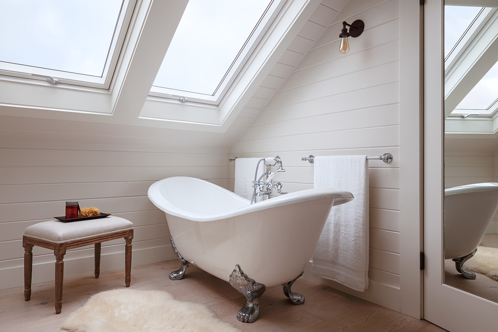 This is an example of a traditional bathroom in San Francisco with a claw-foot tub, white walls, light hardwood floors and beige floor.