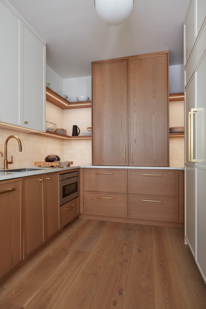 Idéer för stora funkis vitt kök, med släta luckor, skåp i ljust trä, bänkskiva i kvarts, vitt stänkskydd, en köksö, en undermonterad diskho, integrerade vitvaror, ljust trägolv och brunt golv