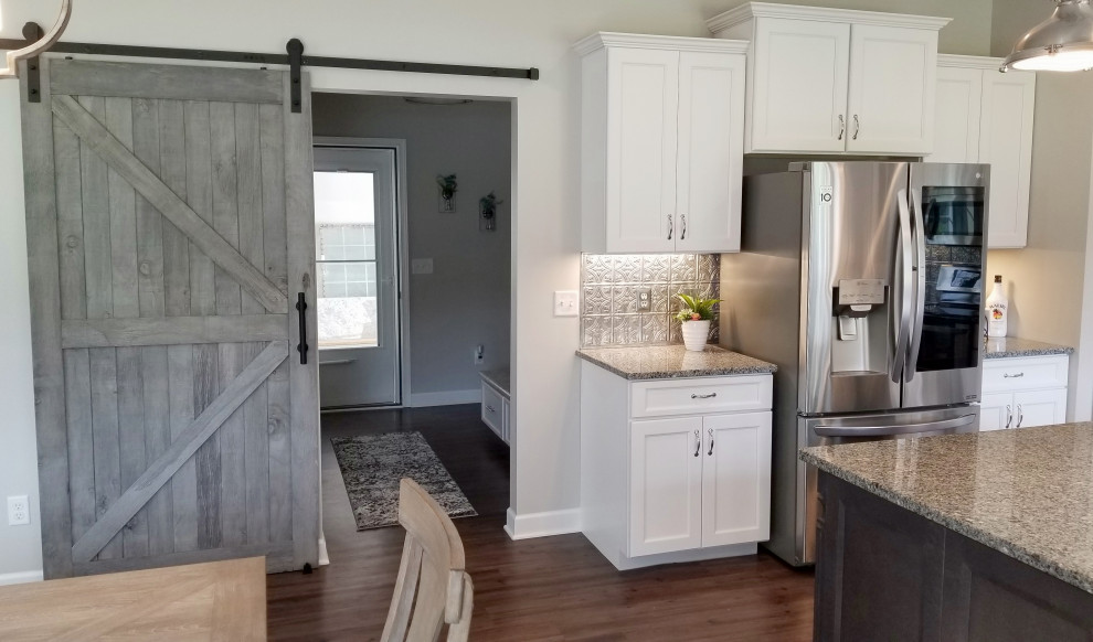 Example of a mid-sized transitional u-shaped vinyl floor and multicolored floor eat-in kitchen design with a farmhouse sink, recessed-panel cabinets, white cabinets, granite countertops, metallic backsplash, metal backsplash, stainless steel appliances, an island and gray countertops
