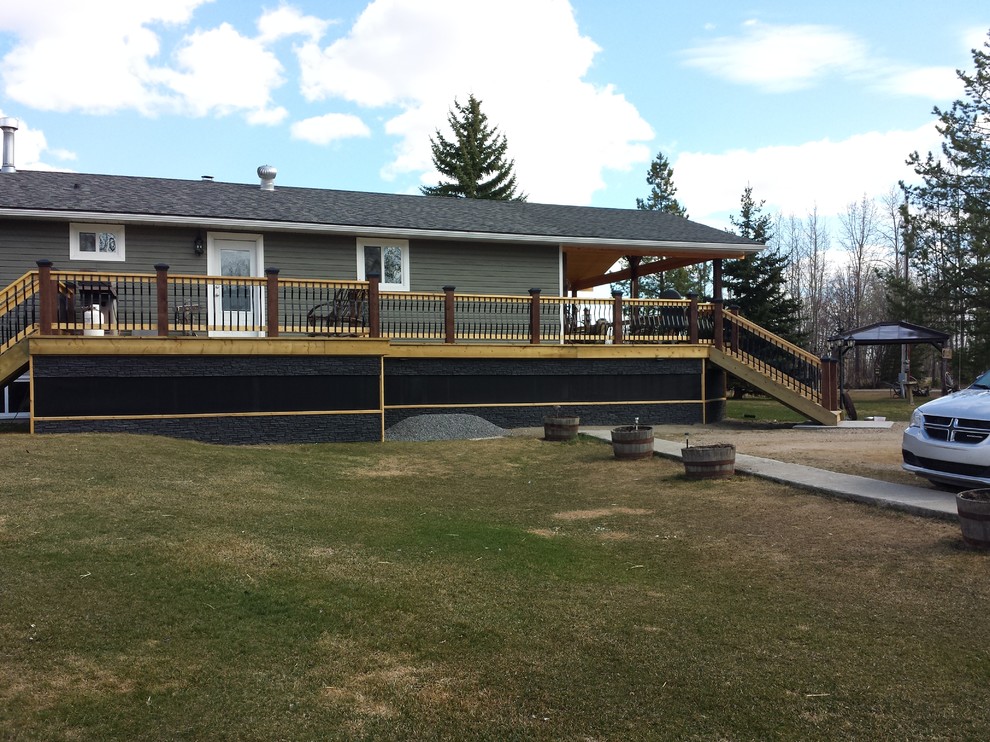 Example of a mid-sized mountain style backyard deck design in Edmonton with a roof extension