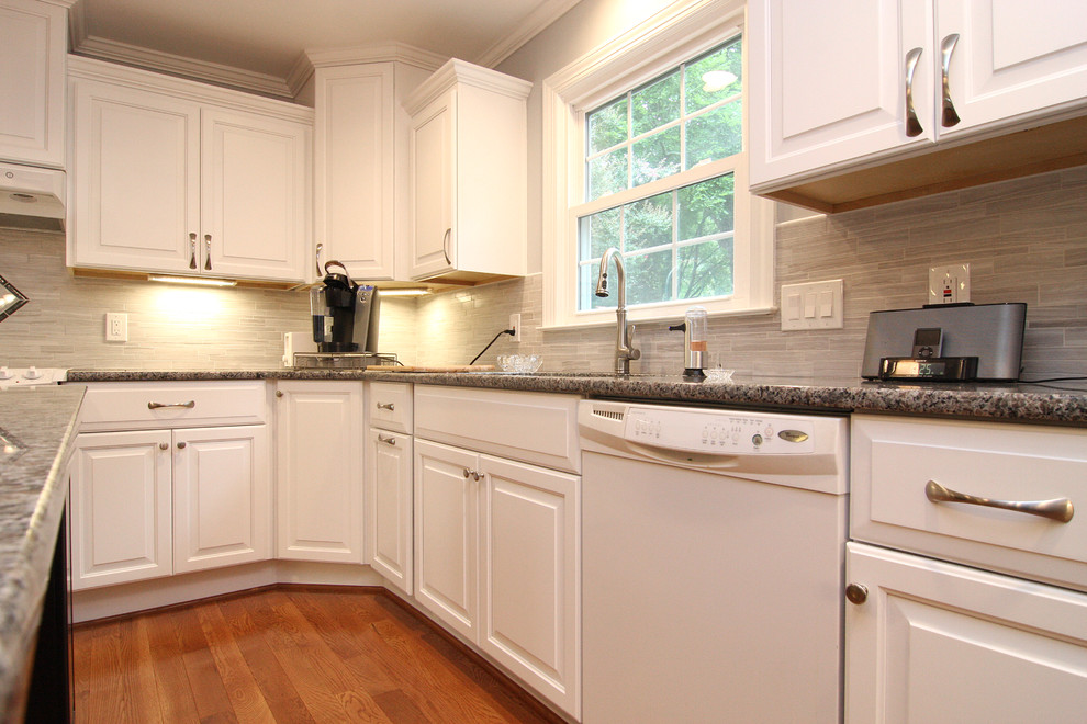 Inspiration for a mid-sized transitional u-shaped medium tone wood floor eat-in kitchen remodel with an undermount sink, raised-panel cabinets, white cabinets, granite countertops, gray backsplash, porcelain backsplash, white appliances and an island