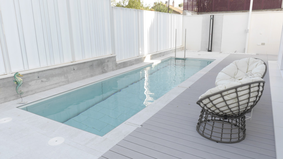 Mid-sized contemporary front yard rectangular lap pool in Madrid with a pool house and tile.