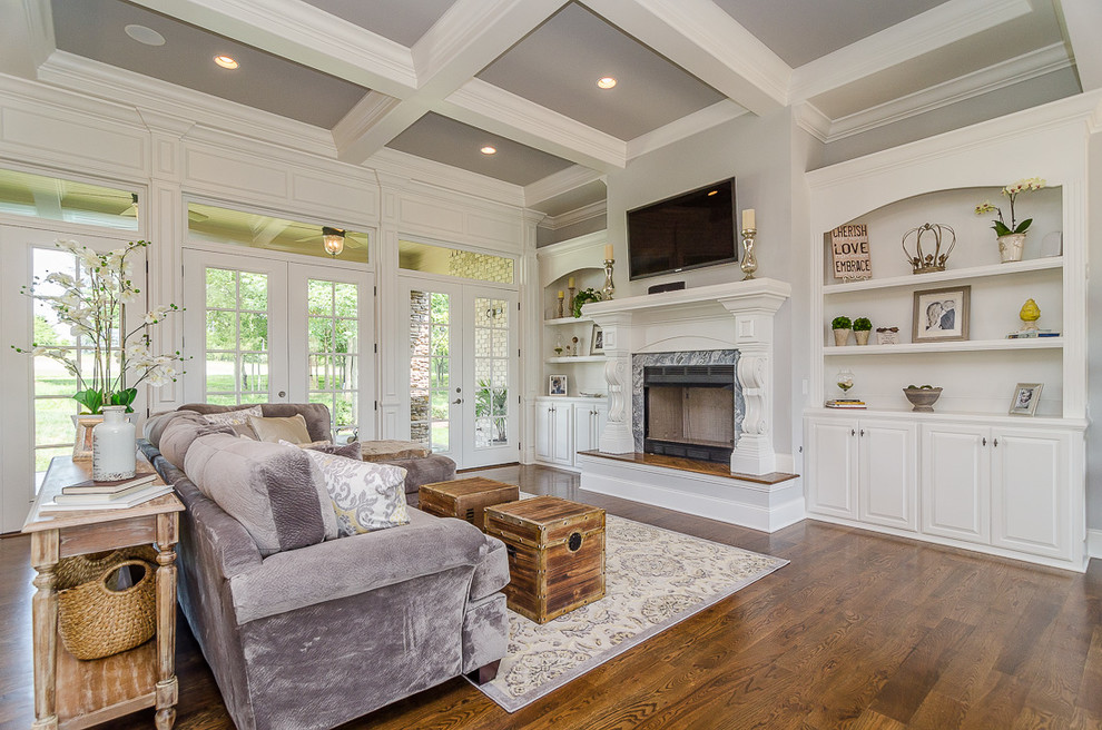 This is an example of a large transitional open concept living room in Nashville with grey walls, dark hardwood floors, a standard fireplace, a stone fireplace surround, a wall-mounted tv and brown floor.