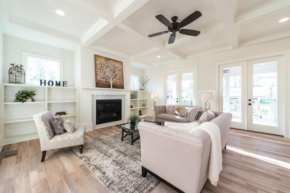 Large arts and crafts open concept family room in Charlotte with white walls, light hardwood floors, a standard fireplace, a tile fireplace surround and beige floor.