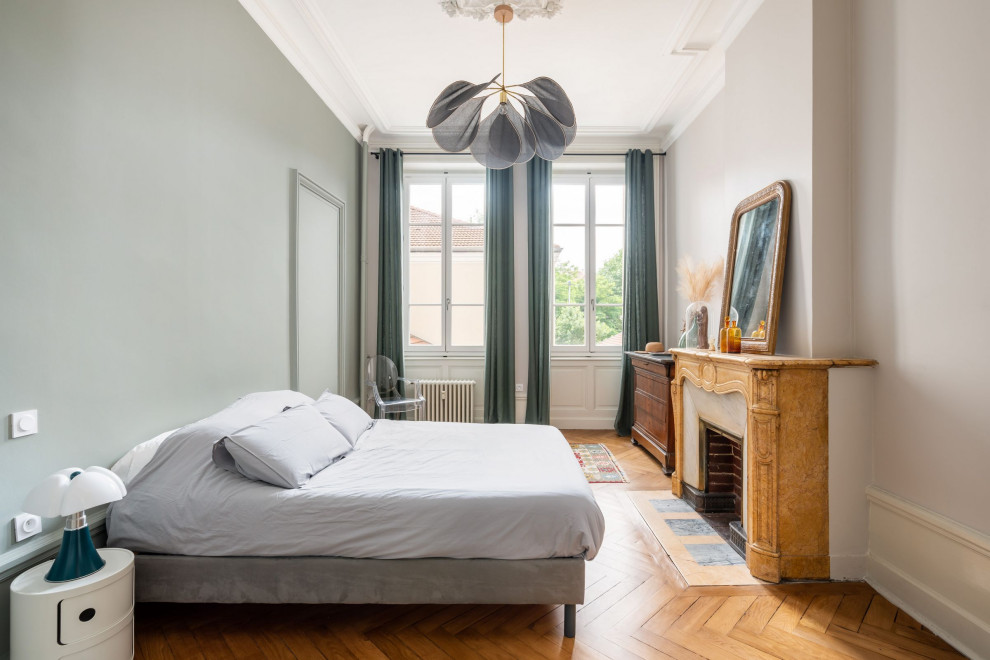 Example of a large master light wood floor bedroom design in Saint-Etienne with green walls and a stone fireplace