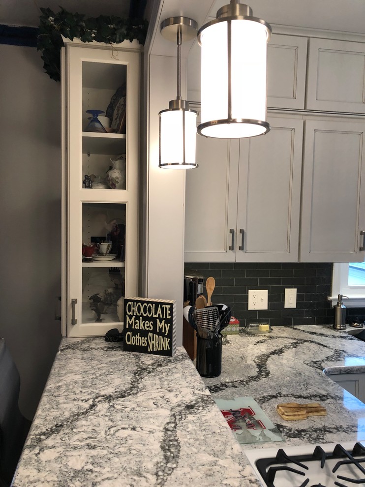 Small transitional l-shaped laminate floor and gray floor eat-in kitchen photo with an undermount sink, flat-panel cabinets, white cabinets, quartz countertops, gray backsplash, subway tile backsplash, white appliances and white countertops
