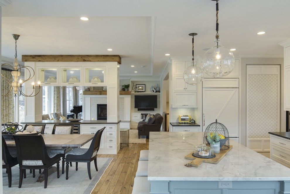 This is an example of a large country l-shaped eat-in kitchen in Minneapolis with a farmhouse sink, recessed-panel cabinets, white cabinets, marble benchtops, white splashback, ceramic splashback, panelled appliances, medium hardwood floors and with island.