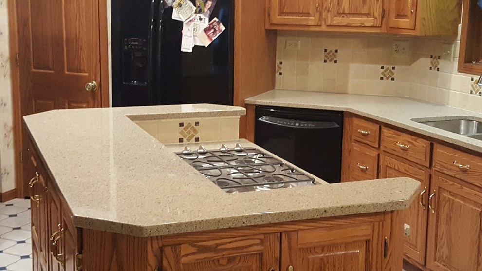 Photo of a mid-sized country l-shaped separate kitchen in Chicago with an undermount sink, raised-panel cabinets, medium wood cabinets, quartz benchtops, beige splashback, ceramic splashback, black appliances, ceramic floors, with island and white floor.
