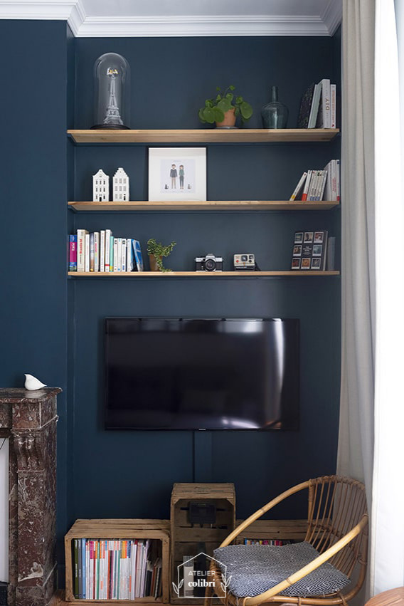На фото: открытая гостиная комната среднего размера в стиле модернизм с синими стенами, светлым паркетным полом, стандартным камином, фасадом камина из камня, телевизором на стене и коричневым полом
