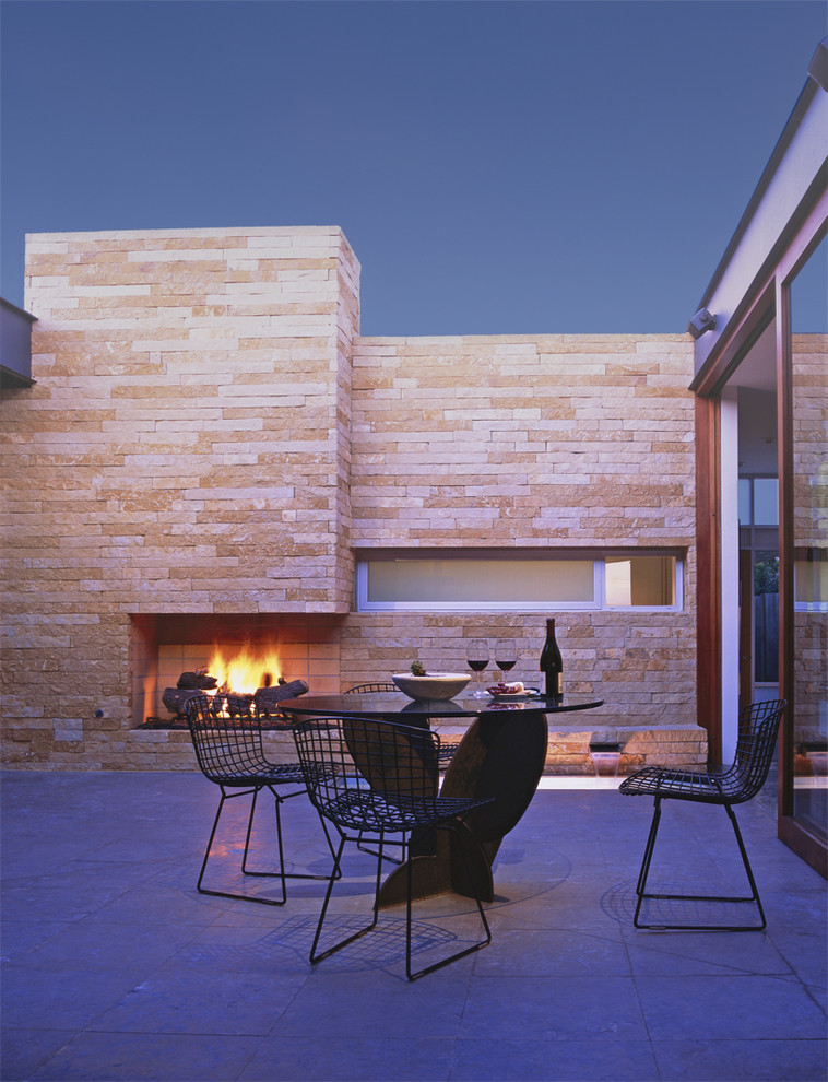 This is an example of a mid-sized midcentury backyard patio in Orange County with a fire feature, stamped concrete and no cover.