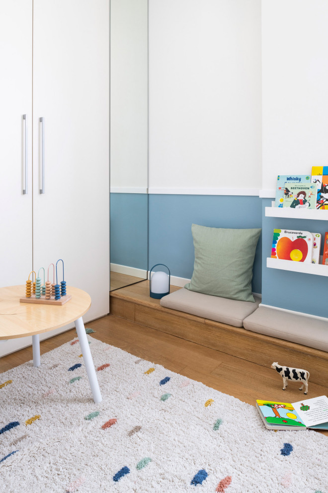 Esempio di una grande cameretta per bambini da 1 a 3 anni minimalista con pareti blu, parquet chiaro e carta da parati