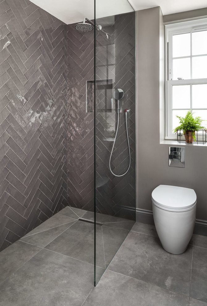 This is an example of a mid-sized contemporary bathroom in London with an open shower, a one-piece toilet, gray tile, ceramic tile, grey walls, porcelain floors, grey floor and a hinged shower door.