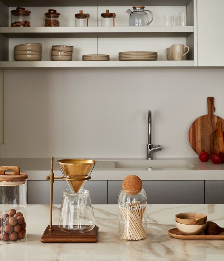 Bild på ett mellanstort funkis beige beige kök och matrum, med en nedsänkt diskho, släta luckor, skåp i rostfritt stål, bänkskiva i koppar, beige stänkskydd, glaspanel som stänkskydd och en köksö