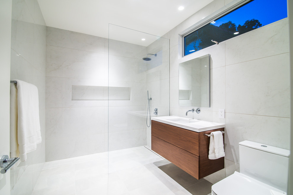 Large contemporary bathroom in Los Angeles with flat-panel cabinets, a curbless shower, a one-piece toilet, stone tile, porcelain floors, an undermount sink, engineered quartz benchtops, an open shower, white benchtops, dark wood cabinets, gray tile and grey floor.