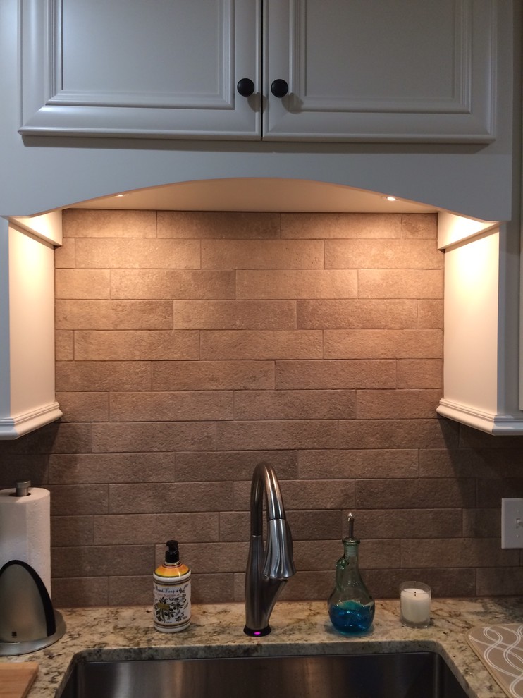 Large transitional l-shaped brown floor eat-in kitchen photo in Birmingham with a farmhouse sink, recessed-panel cabinets, white cabinets, beige backsplash, stainless steel appliances and an island