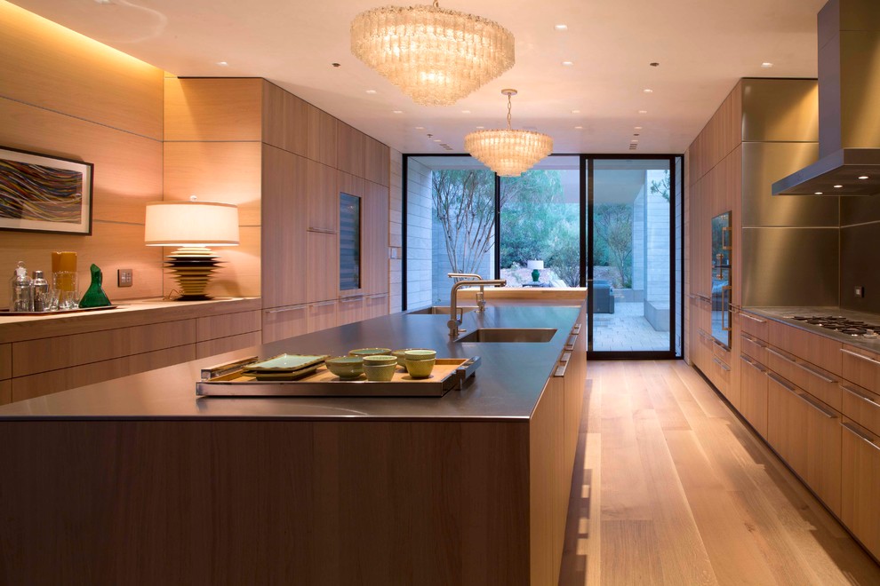 Photo of a modern u-shaped separate kitchen in Phoenix with an integrated sink, flat-panel cabinets, light wood cabinets, stainless steel benchtops and panelled appliances.