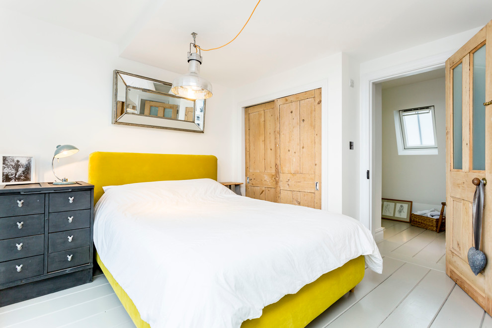 Design ideas for a beach style master bedroom in Hampshire with painted wood floors.