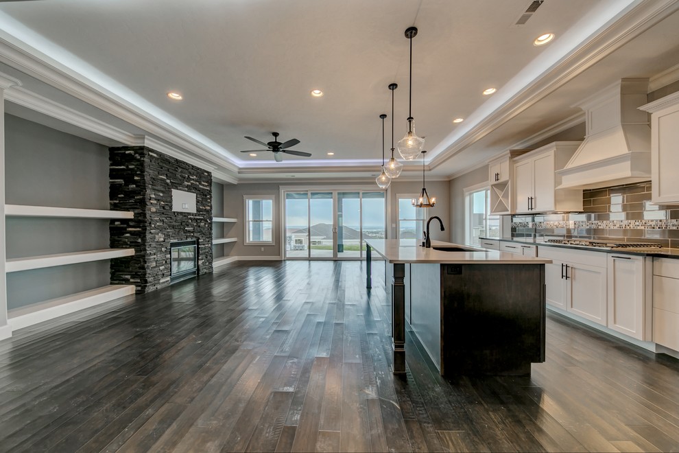 Example of a mid-sized transitional single-wall medium tone wood floor open concept kitchen design in Seattle with an undermount sink, shaker cabinets, white cabinets, gray backsplash, glass tile backsplash, stainless steel appliances, an island and quartz countertops
