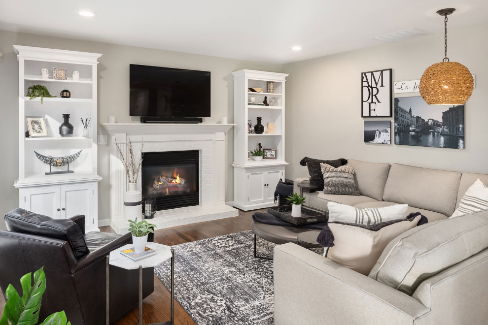 Large transitional living room in Seattle with grey walls, medium hardwood floors, a standard fireplace, a brick fireplace surround, a wall-mounted tv and brown floor.
