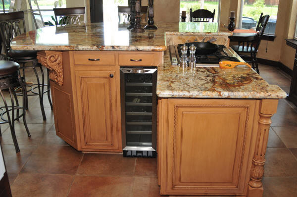 Large transitional l-shaped porcelain tile and brown floor eat-in kitchen photo in Houston with a double-bowl sink, raised-panel cabinets, medium tone wood cabinets, granite countertops, beige backsplash, travertine backsplash, stainless steel appliances and an island