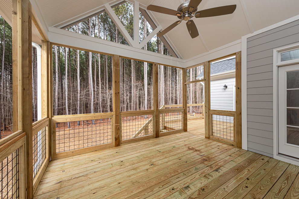 Large traditional backyard screened-in verandah in Raleigh with decking, a roof extension and mixed railing.