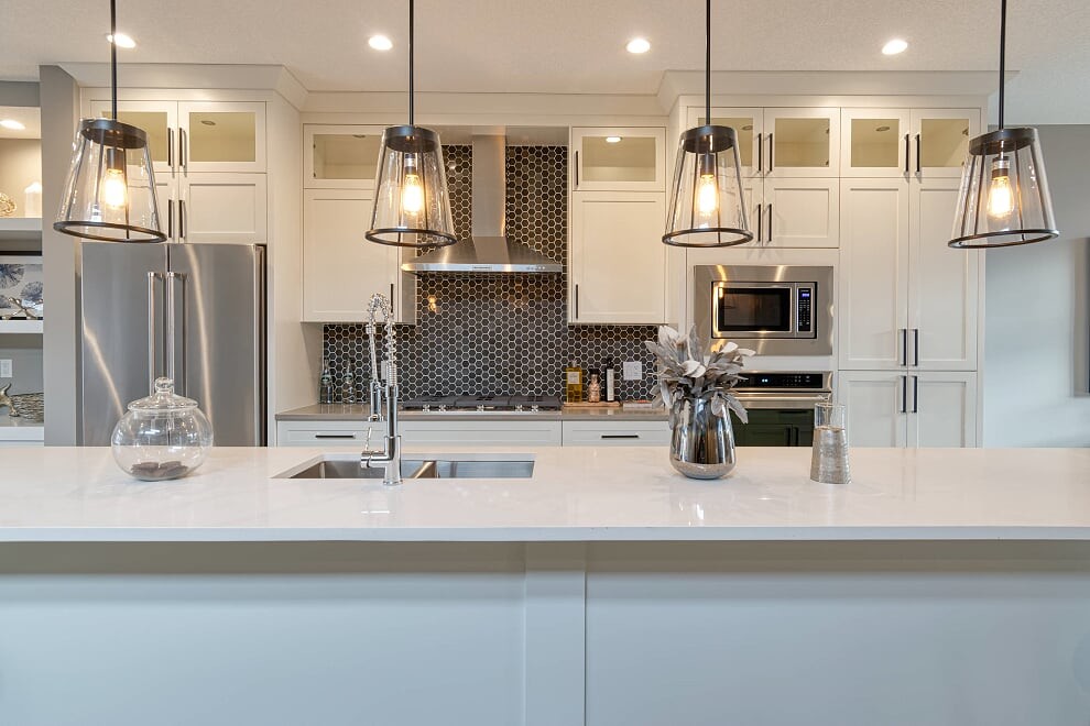 Inspiration for a large transitional u-shaped vinyl floor and gray floor eat-in kitchen remodel with an undermount sink, recessed-panel cabinets, white cabinets, quartzite countertops, black backsplash, mosaic tile backsplash, stainless steel appliances, an island and white countertops