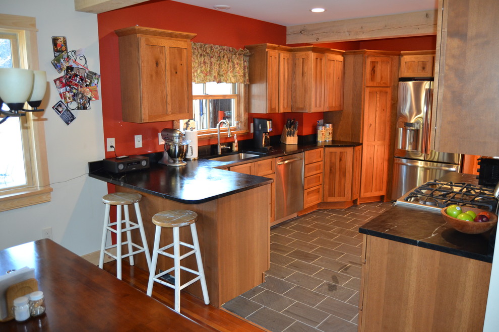 Eat-in kitchen - mid-sized rustic l-shaped slate floor eat-in kitchen idea in Burlington with an undermount sink, shaker cabinets, distressed cabinets, soapstone countertops and stainless steel appliances