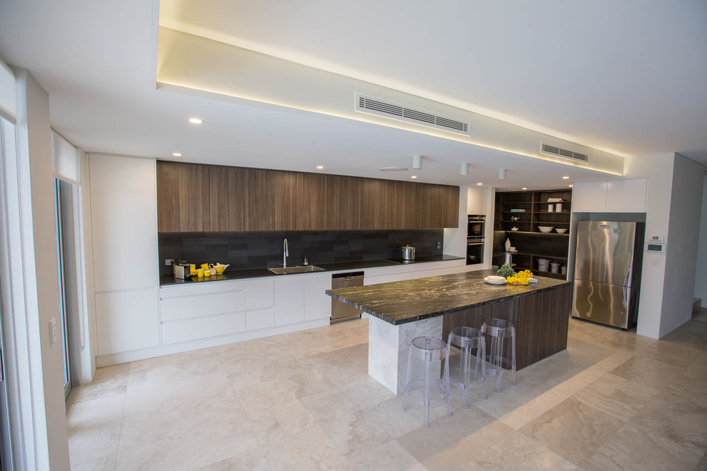 Large modern single-wall eat-in kitchen in Sydney with a drop-in sink, flat-panel cabinets, medium wood cabinets, granite benchtops, black splashback, ceramic splashback, stainless steel appliances, ceramic floors, with island and grey floor.