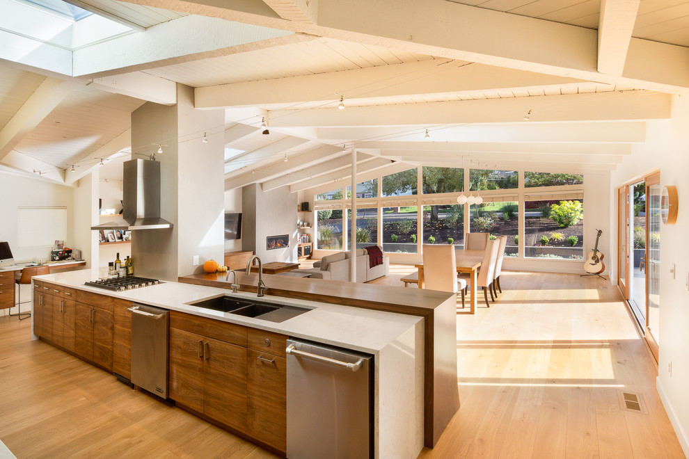 Inspiration for a midcentury galley open plan kitchen in Portland with an undermount sink, flat-panel cabinets, medium wood cabinets, quartz benchtops, grey splashback, stainless steel appliances, light hardwood floors and with island.