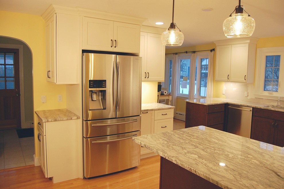 Example of a mid-sized transitional u-shaped light wood floor eat-in kitchen design in Boston with an undermount sink, shaker cabinets, white cabinets, quartz countertops, stainless steel appliances and a peninsula
