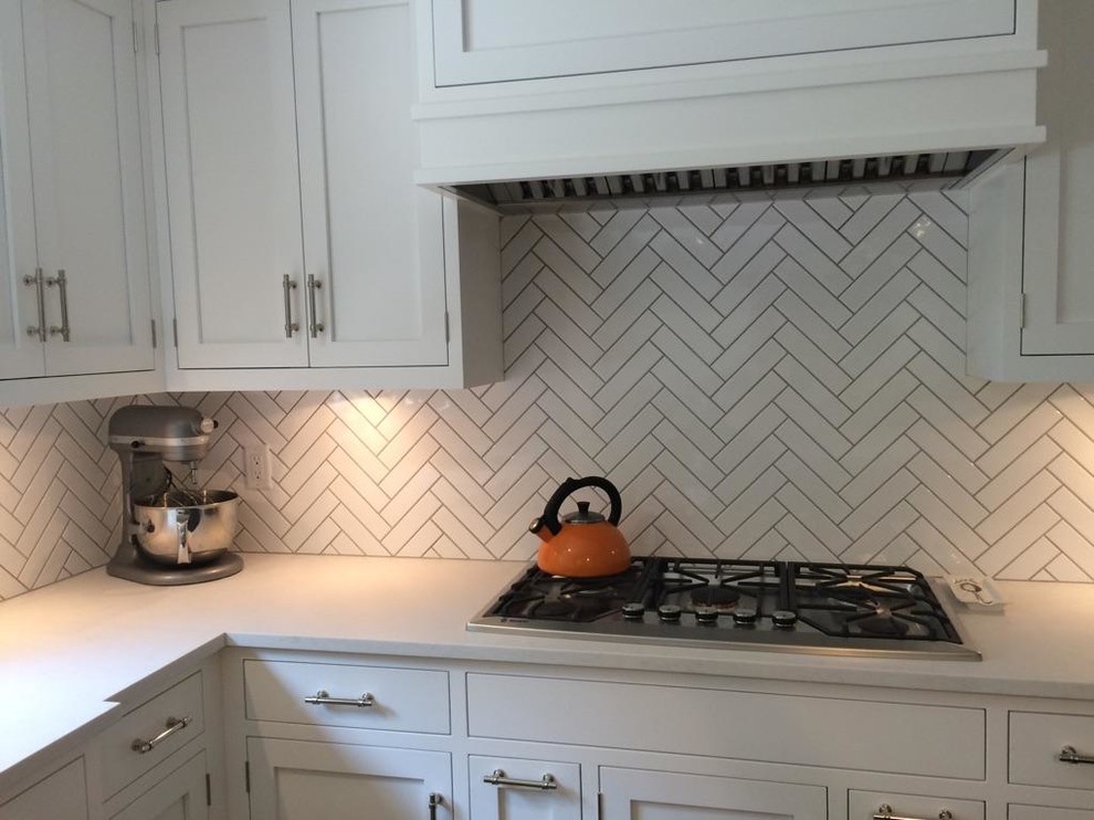 Mid-sized transitional l-shaped dark wood floor and brown floor open concept kitchen photo in New York with an undermount sink, shaker cabinets, white cabinets, limestone countertops, white backsplash, porcelain backsplash, stainless steel appliances and an island