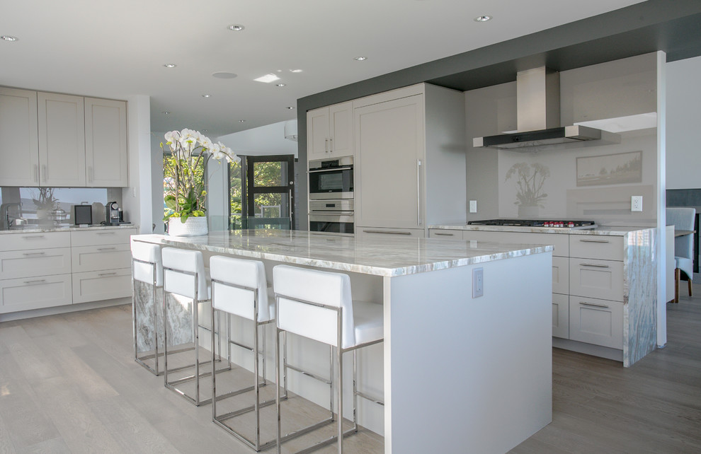This is an example of a large contemporary l-shaped open plan kitchen in Vancouver with shaker cabinets, grey cabinets, grey splashback, with island, granite benchtops, panelled appliances and medium hardwood floors.