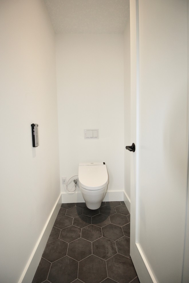 This is an example of a mid-sized contemporary powder room in Calgary with flat-panel cabinets, light wood cabinets, subway tile, white walls, cement tiles, a vessel sink, solid surface benchtops, grey floor and white benchtops.