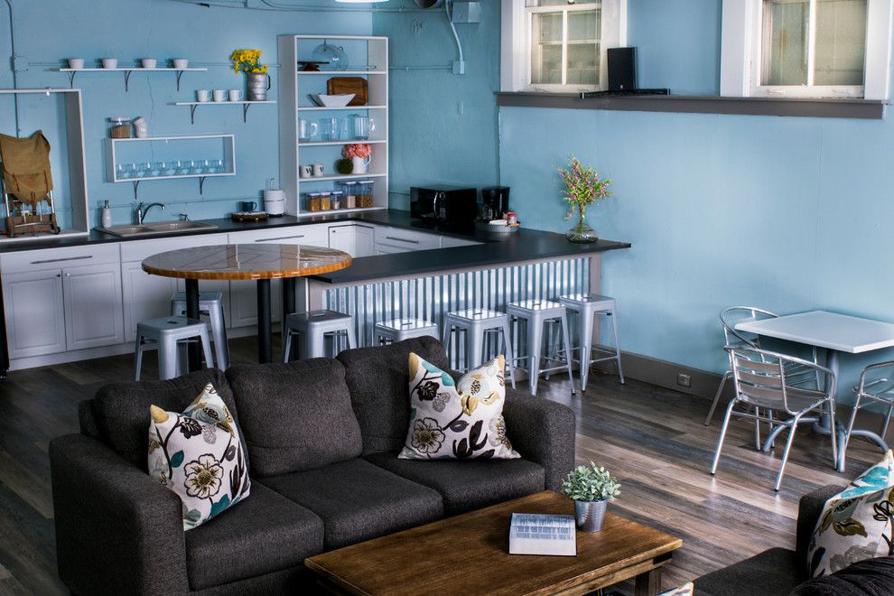 Example of a mid-sized transitional u-shaped and look-out medium tone wood floor and brown floor basement design in Indianapolis with blue walls, a drop-in sink, open cabinets, white cabinets, quartz countertops, black appliances, a peninsula and no fireplace
