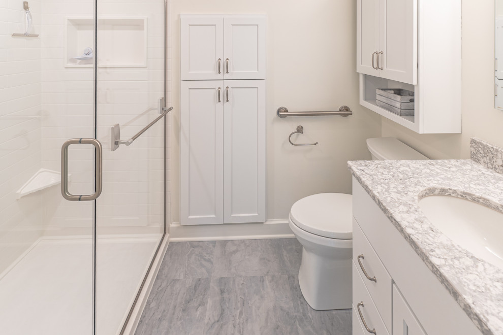 Inspiration for a medium sized traditional bathroom in Milwaukee with shaker cabinets, white cabinets, an alcove shower, a two-piece toilet, white walls, wood-effect flooring, a submerged sink, engineered stone worktops, grey floors, a hinged door, multi-coloured worktops, a wall niche, a single sink and a built in vanity unit.