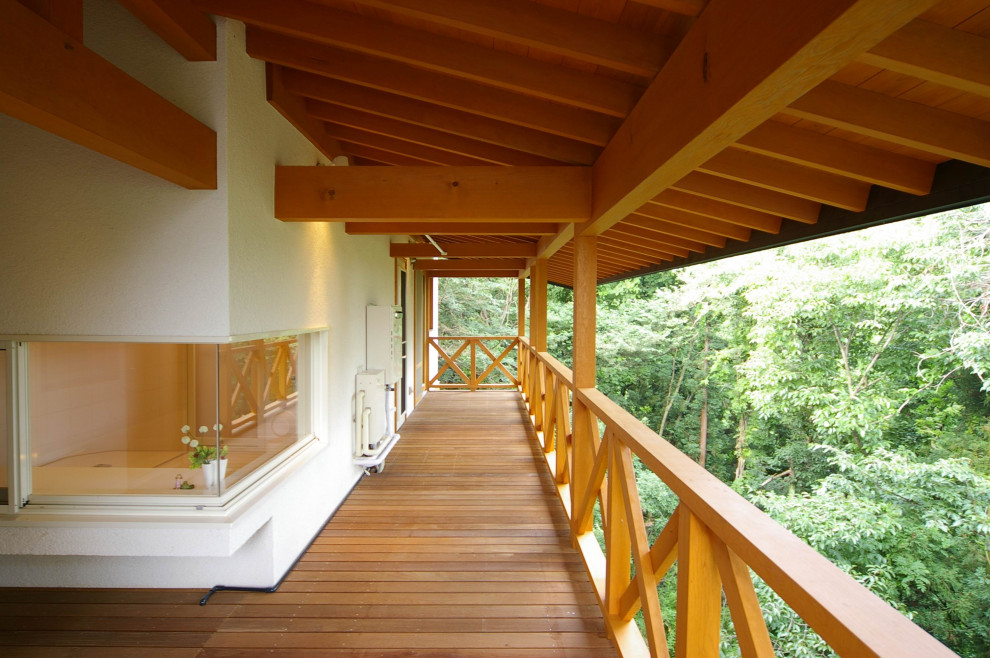 Exemple d'une grande terrasse latérale moderne avec jupe de finition et une extension de toiture.