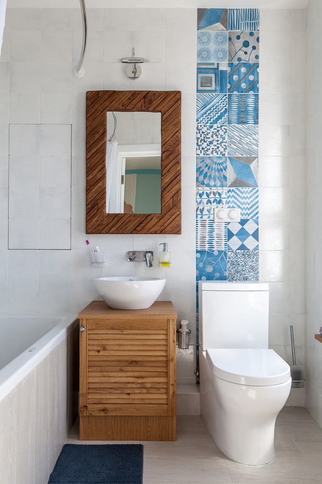 Inspiration for a mid-sized beach style master bathroom in Moscow with a two-piece toilet, blue tile, white tile, ceramic tile, ceramic floors, wood benchtops, beige floor, brown benchtops, louvered cabinets, medium wood cabinets, a shower/bathtub combo, a vessel sink and a shower curtain.