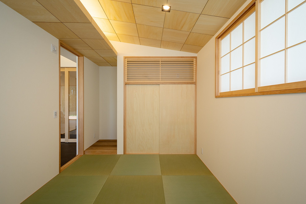 На фото: изолированная гостиная комната среднего размера с белыми стенами, татами, зеленым полом, деревянным потолком и обоями на стенах без камина, телевизора с