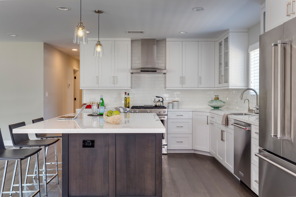 Design ideas for a mid-sized transitional l-shaped open plan kitchen in Los Angeles with an undermount sink, shaker cabinets, white cabinets, quartz benchtops, white splashback, subway tile splashback, stainless steel appliances, dark hardwood floors, with island and brown floor.
