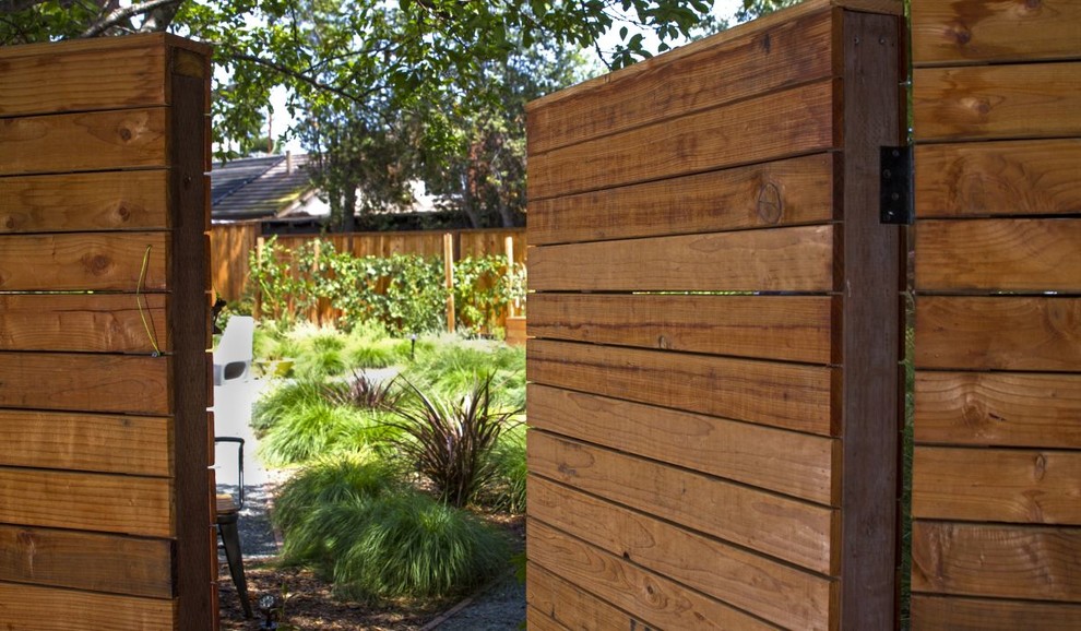 This is an example of a medium sized world-inspired side xeriscape partial sun garden in San Francisco with a gate, decomposed granite and a wood fence.