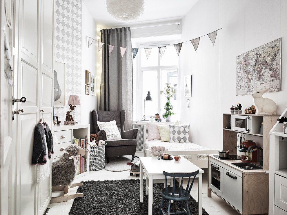 This is an example of a mid-sized scandinavian gender-neutral kids' room in Gothenburg with white walls and painted wood floors.