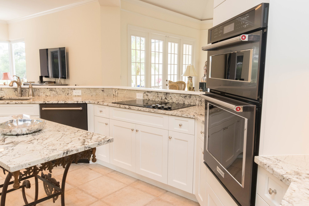 Eat-in kitchen - large transitional porcelain tile eat-in kitchen idea in Miami with an undermount sink, shaker cabinets, white cabinets, granite countertops, gray backsplash, stone slab backsplash, black appliances and an island