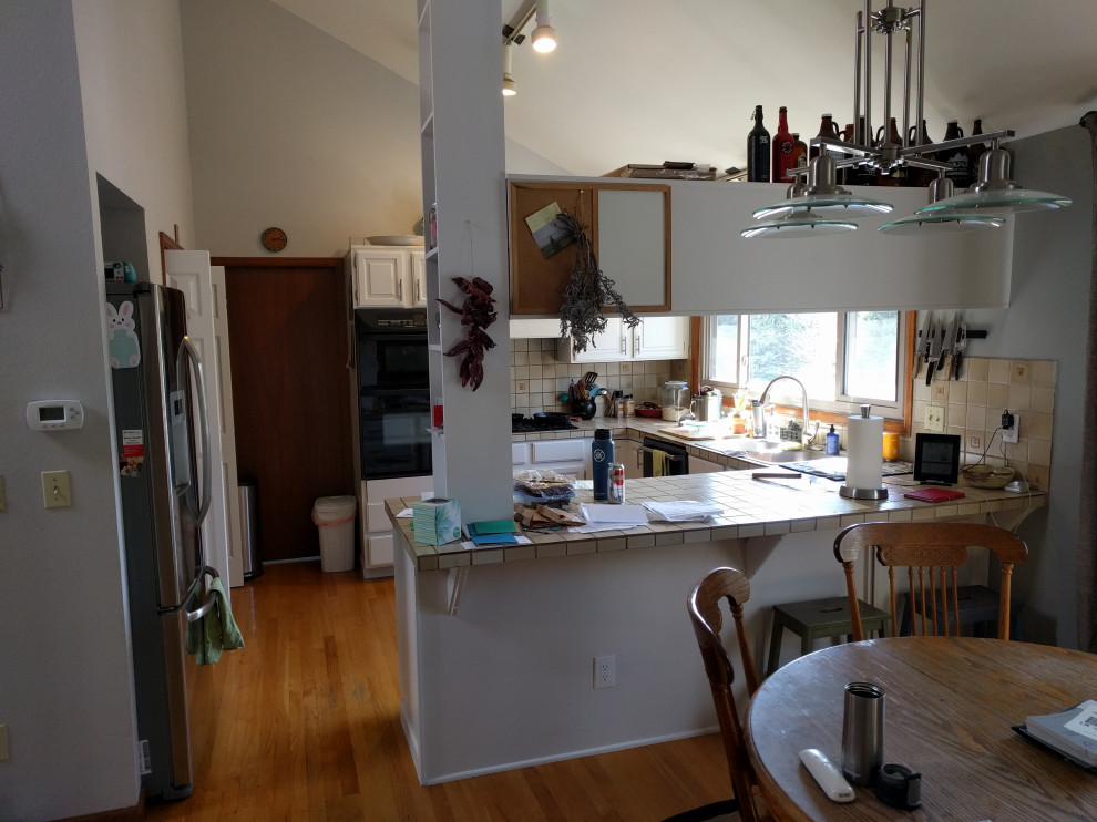 Mid-sized transitional u-shaped medium tone wood floor and multicolored floor kitchen photo in Denver with a farmhouse sink, shaker cabinets, brown cabinets, granite countertops, beige backsplash, subway tile backsplash, stainless steel appliances, an island and multicolored countertops