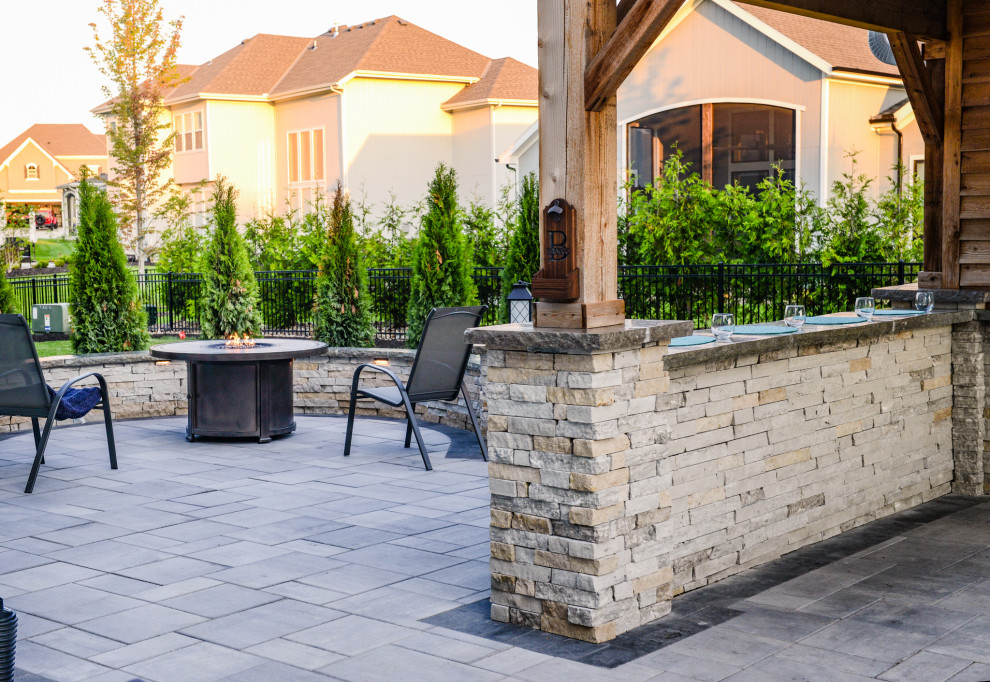 Inspiration for a large contemporary backyard patio in Kansas City with concrete pavers and a roof extension.